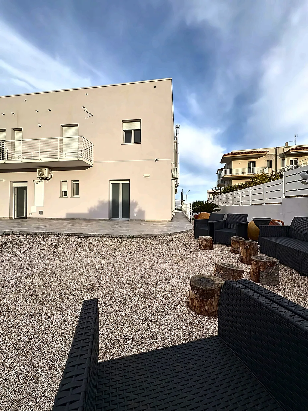 L'area relax con divani e sgabelli in legno, con la casa bianca sullo sfondo